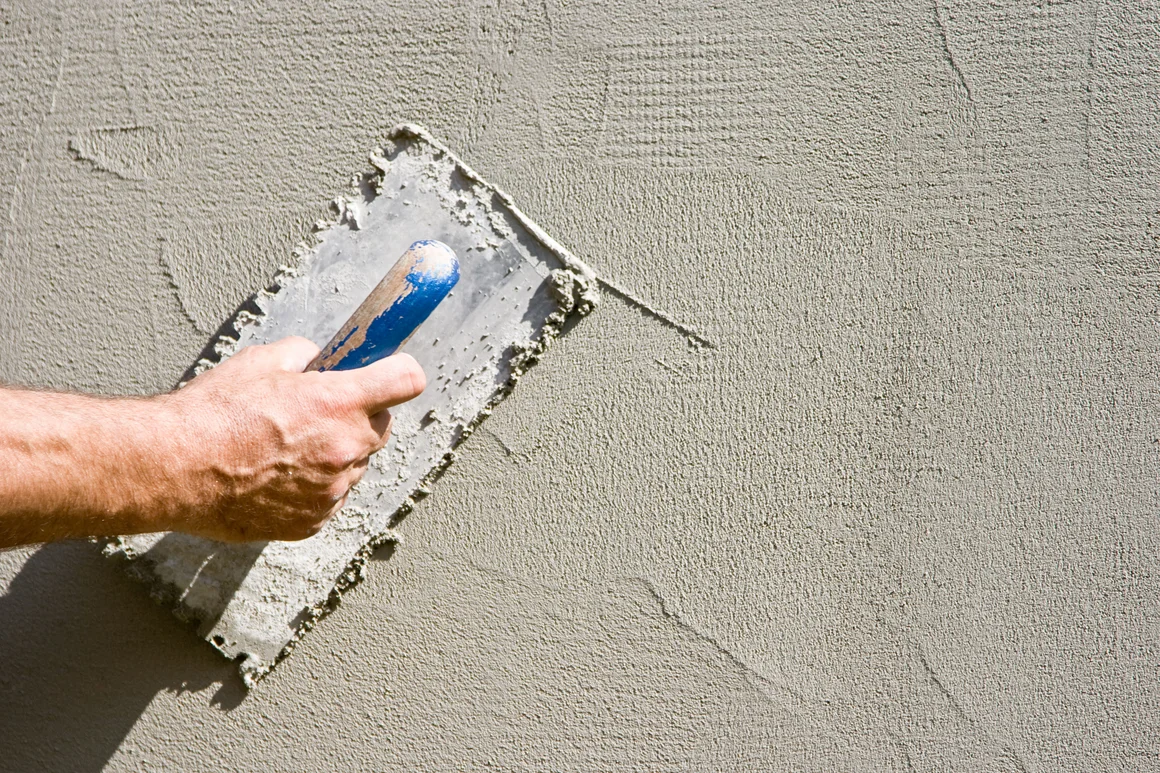 Person verputzt Wand mit Kelle